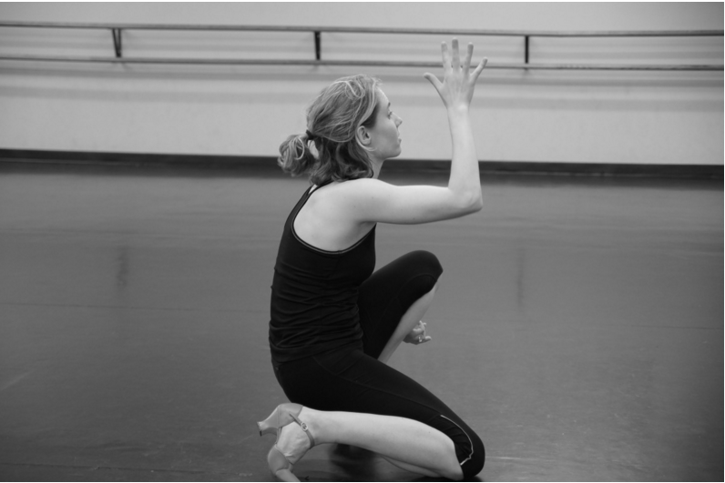 Clare in the studio. She crouches near the ground in character shoes.